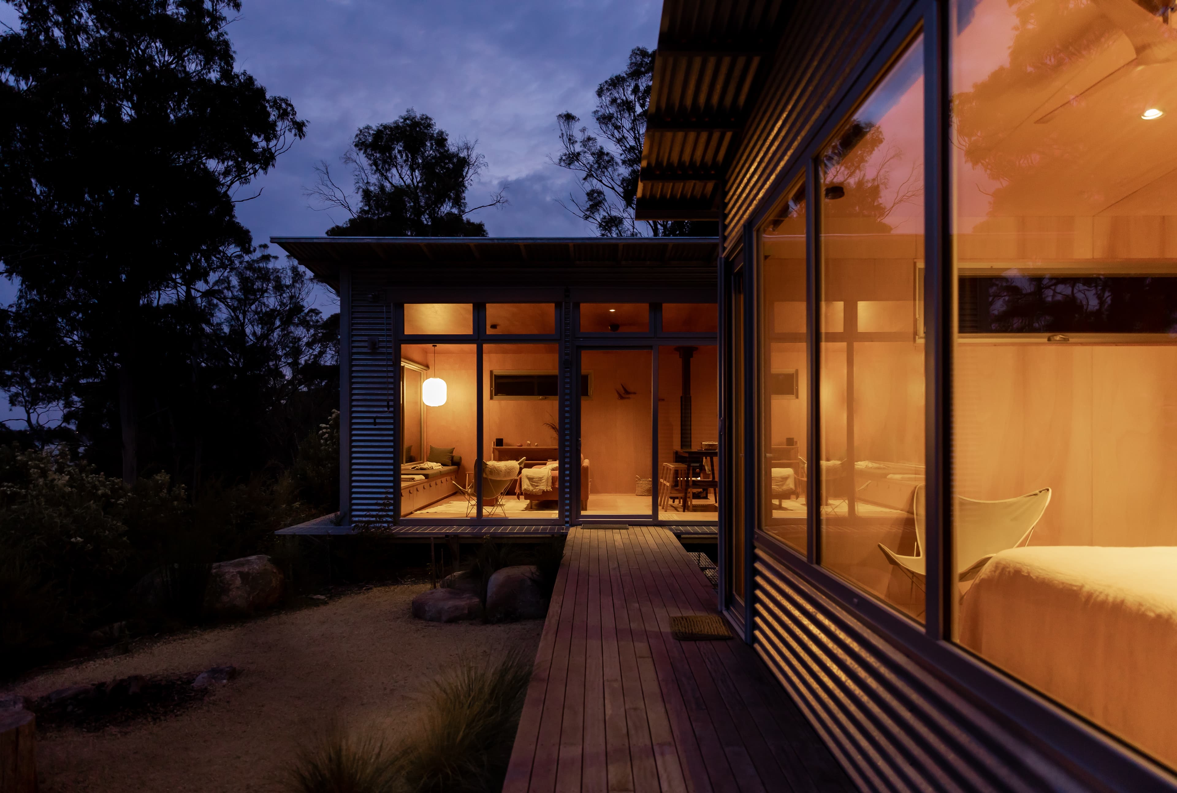 Timber walkway between glowing pavilions at dusk