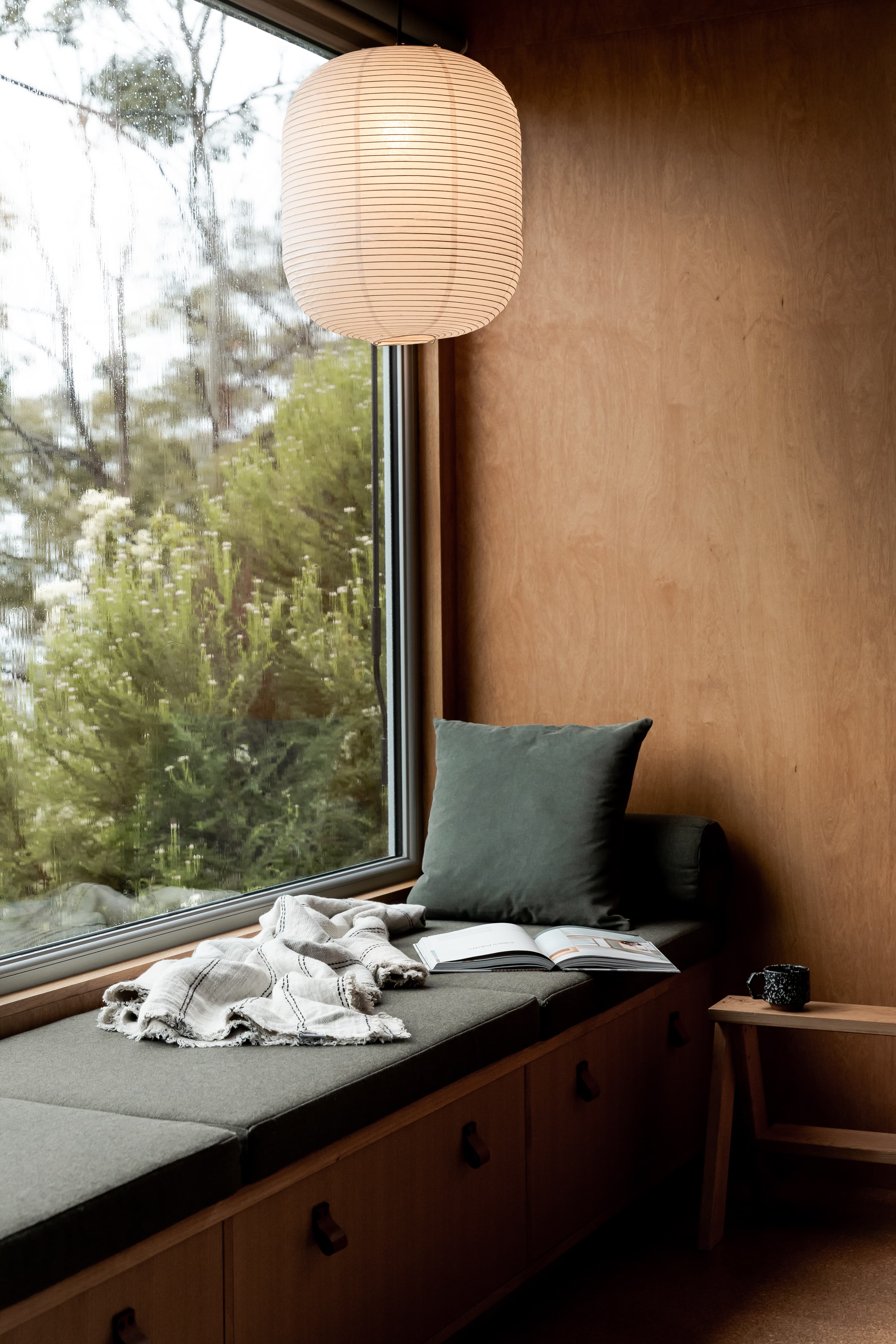 Cushioned reading nook beside a rain-speckled window